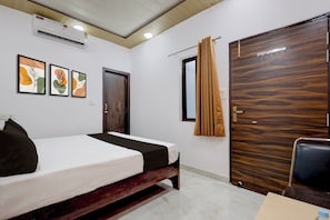 A hotel room with a bed, a wooden wardrobe, a window with curtains, and wall art. - HOTEL O YASH ROYAL INN (Lucknow)