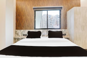 Una habitación de hotel con cama, ventana y vistas a rascacielos.