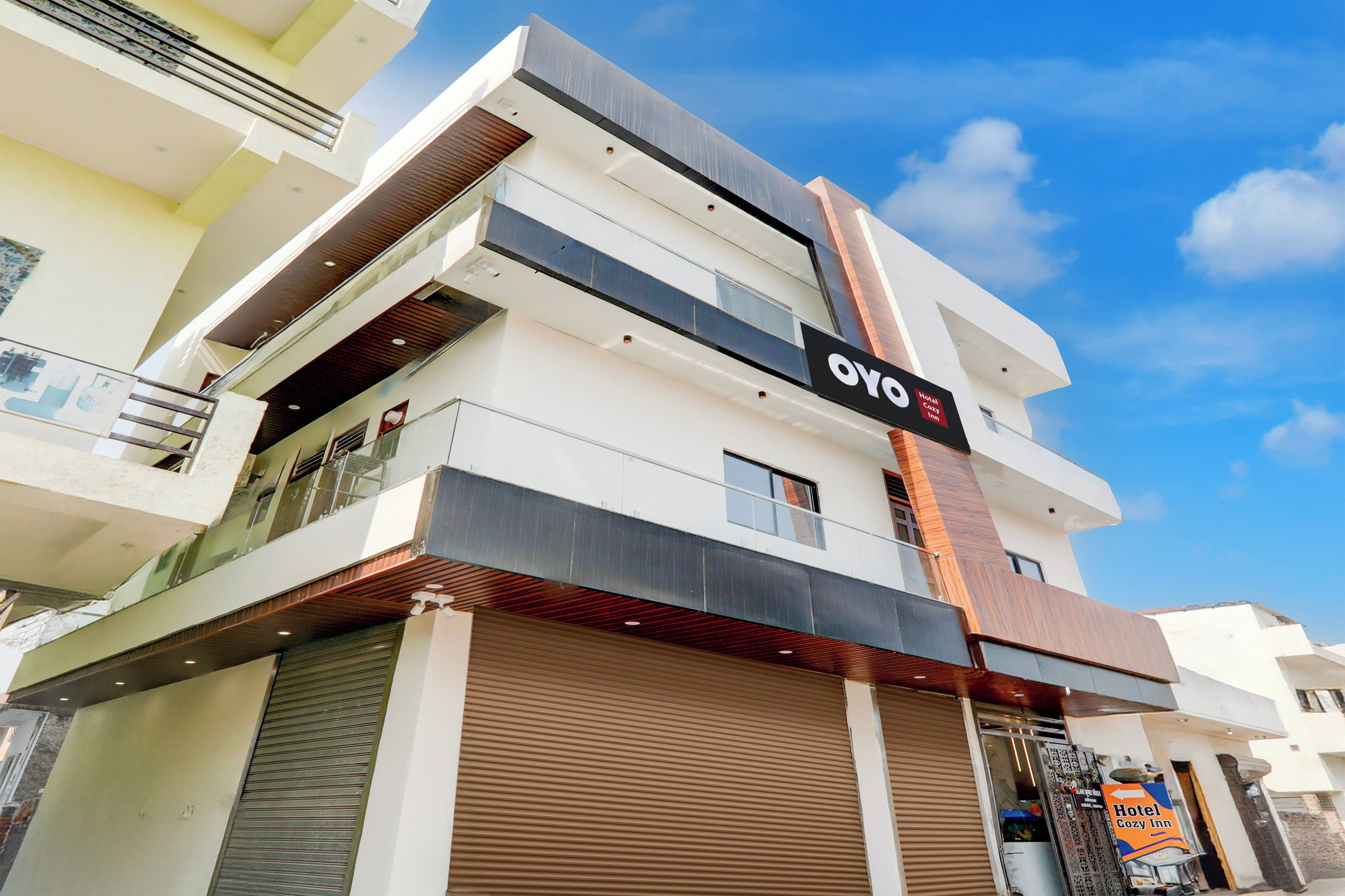 Un moderno edificio de hotel con un letrero llamativo que dice 'OYO Hotel Cozy Inn'.