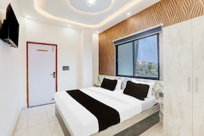Un dormitorio moderno con una cama grande, una ventana con vistas, una puerta y un televisor montado en la pared.