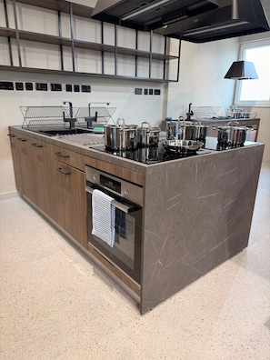 A modern kitchen with a central island, stainless steel appliances, and a built-in oven. - Campus Hub Plus  (Msida)