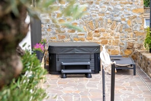 Un mur en pierre agrémenté d’un barbecue et d’un espace détente avec des sièges.