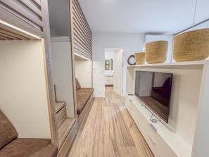 Un intérieur moderne avec un plancher en bois, un canapé, un téléviseur fixé au mur et un escalier.