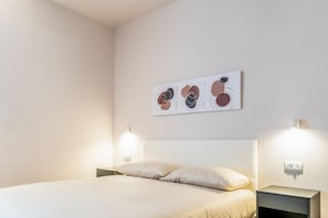 Un dormitorio con una cama, dos lámparas de noche y una obra de arte abstracta colgada en la pared.