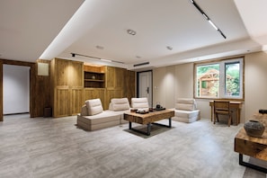 Una sala de estar moderna con un sofá modular, una mesa de centro de madera y vistas al exterior a través de un ventanal.
