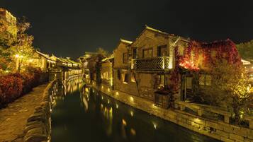 A traditional building with a waterway in front, stone walls, and a wooden bridge.