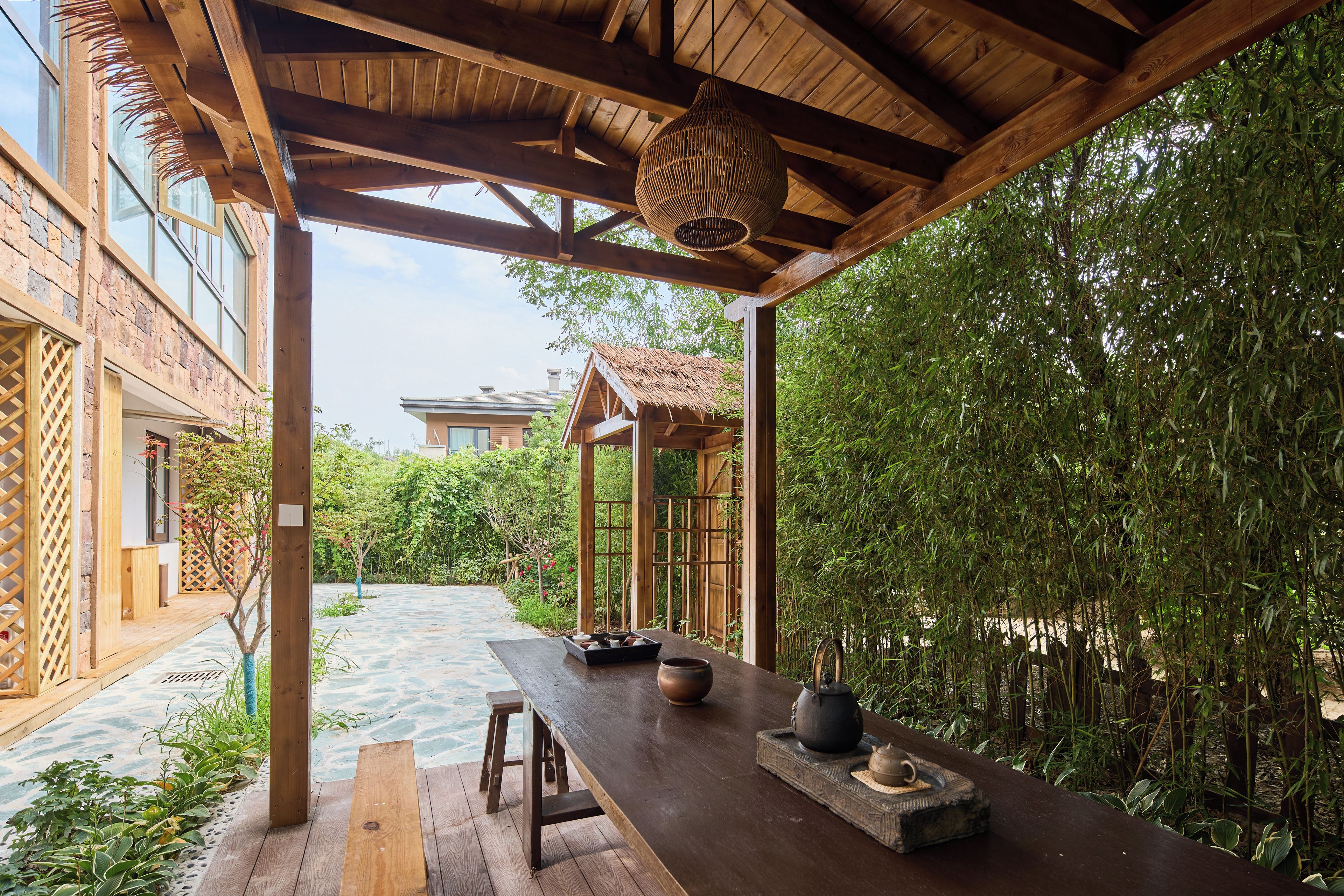 A wooden outdoor seating area with a table, stools, and traditional tea set.