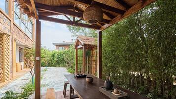 A wooden outdoor seating area with a table, stools, and traditional tea set.