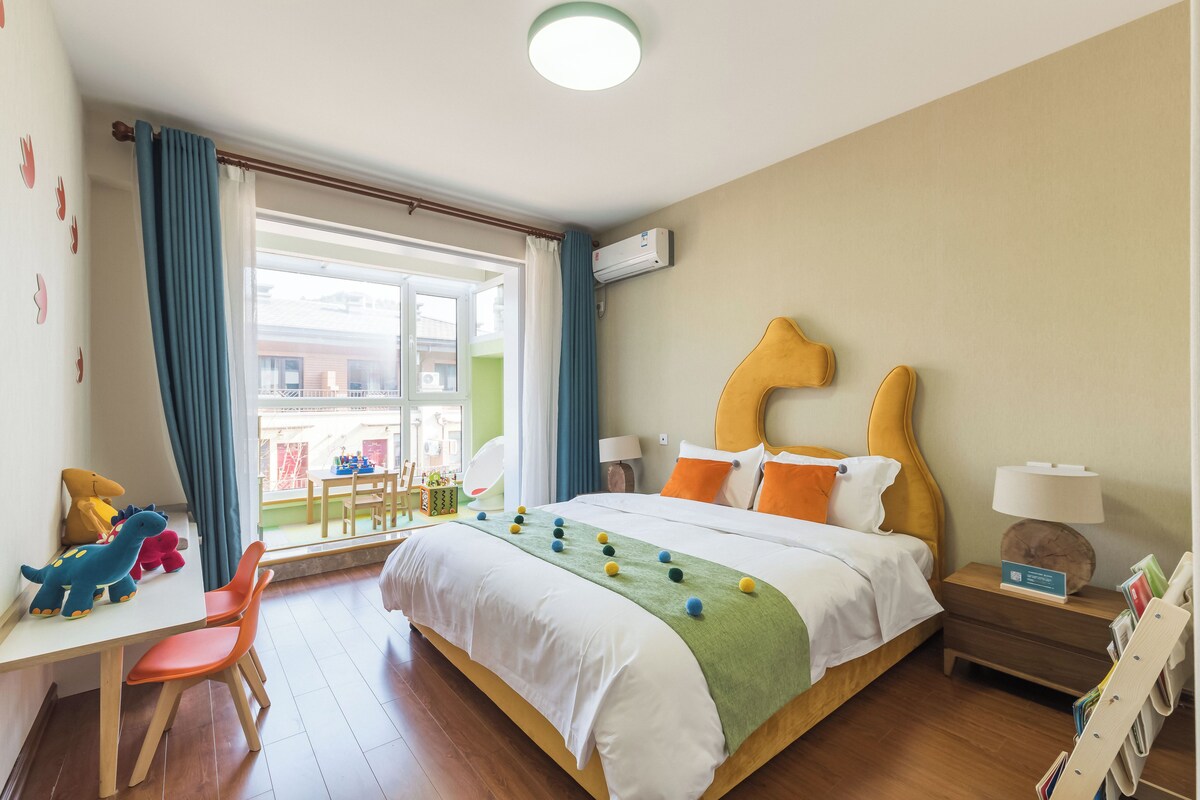 Hotellihuone, jossa on sänky, työpöytä, tuoli, ikkuna verhoilla ja näkymä ulos.