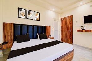 A hotel room with a bed, a bedside table, a telephone, a wall-mounted television, and framed artwork above the bed. - Hotel O Pinaki House (Lucknow)
