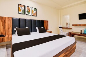 A hotel room with a large bed, a wooden headboard, a flat-screen TV mounted on the wall, and artwork above the bed. - Hotel O Pinaki House (Lucknow)
