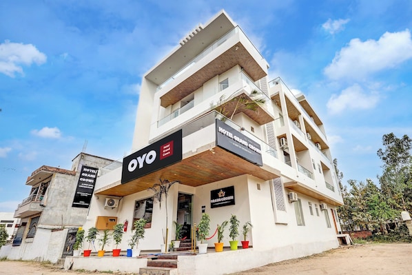 A multi-story hotel with a prominent 'OYO' sign, balconies, and a variety of potted plants. - Hotel O Grand Crown (Lucknow)