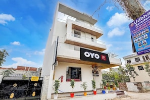 Un hôtel appelé OYO Grand Crown, doté d’une architecture moderne, de nombreux balcons et offrant une vue dégagée sur le ciel.