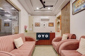 A reception area with a reception desk labeled 'OYO,' two sofas, a ceiling fan, and a clock on the wall. - Hotel O Grand Crown (Lucknow)