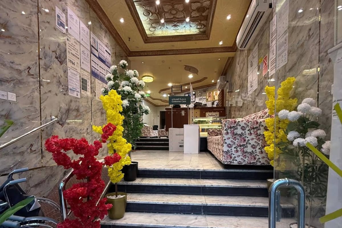 A hotel lobby with marble walls, a staircase, and a customer care desk.