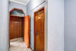 A hallway with two wooden doors, one of which is ajar. - HOTEL O STAY INN (Lucknow)