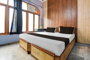 Een slaapkamer met een groot bed, een houten hoofdeinde en een raam met gordijnen.