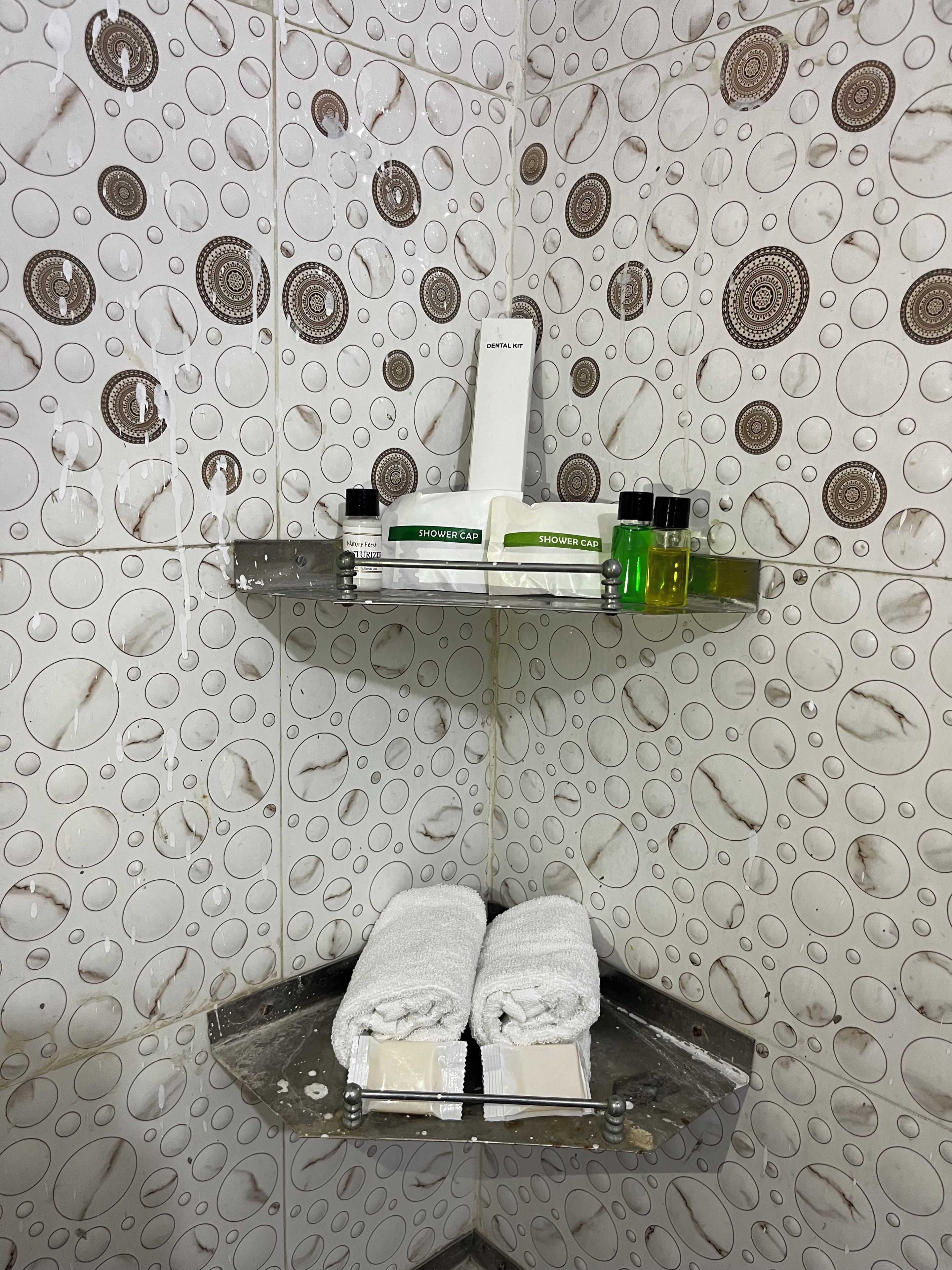 A bathroom with a shower area, a shelf with toiletries, and a towel rack.