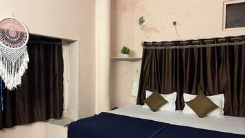 A bedroom with a bed, curtains, a ceiling fan, and a wall-mounted shelf with a plant.