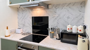 Cozinha moderna com um fogão por indução preto, micro-ondas e torradeira.