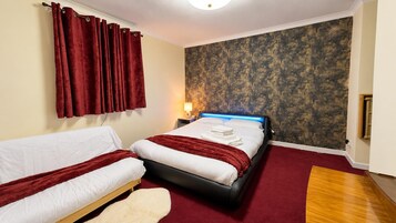 A hotel room with a bed, a sofa, a red carpet, and a textured wall.