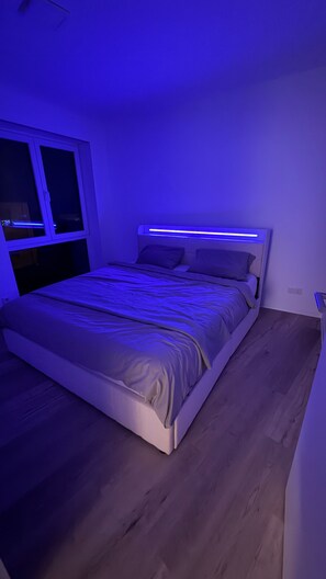 Quarto com cama, janela e luminária fixada na parede.