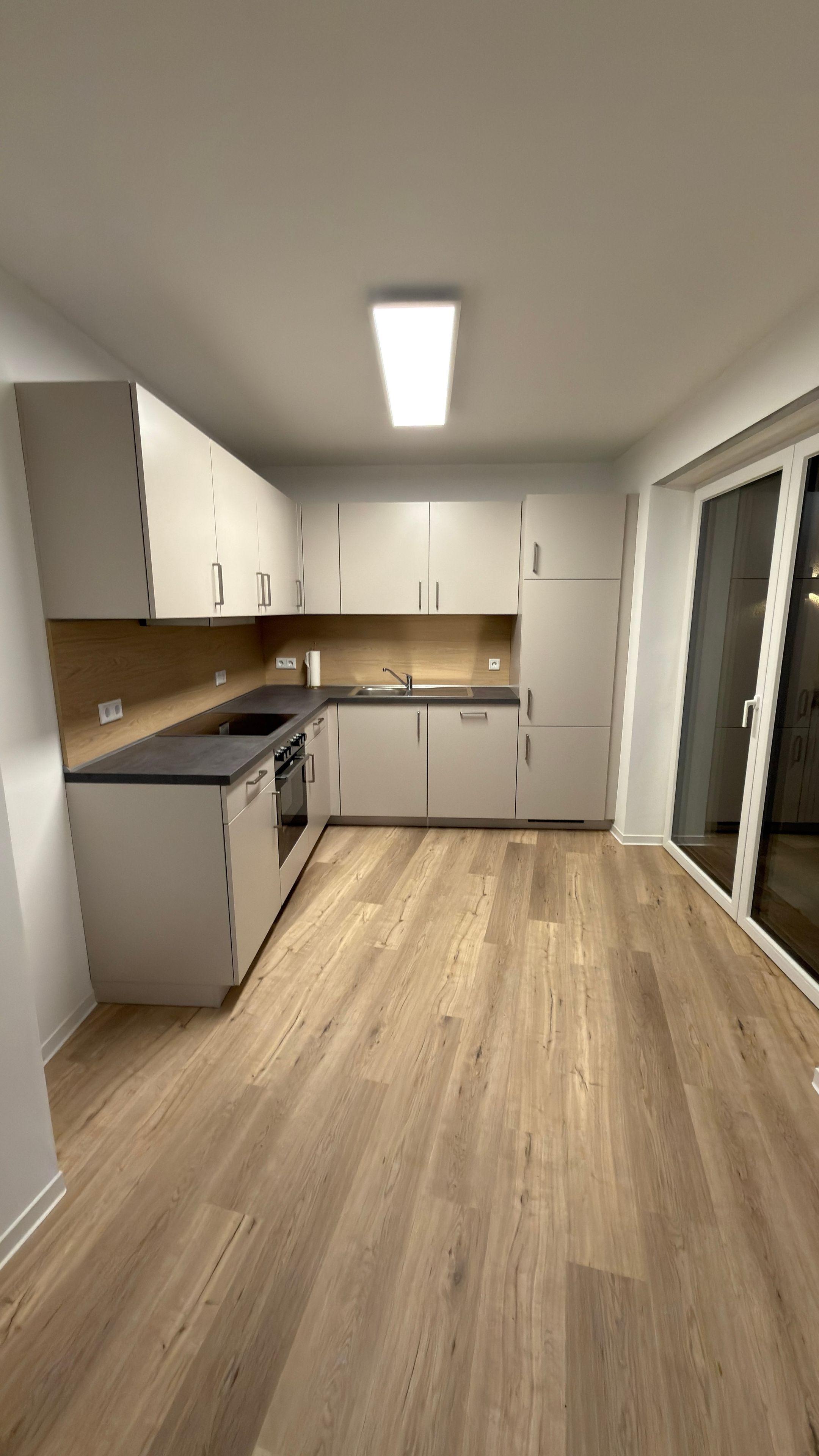 Una cocina moderna con suelo de madera clara, armarios blancos y una isla central.