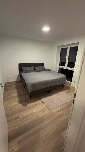 Ein Schlafzimmer mit einem Bett, einem Fenster und einer Tür.