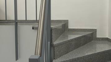 Un escalier avec une rampe métallique et des marches en granit.