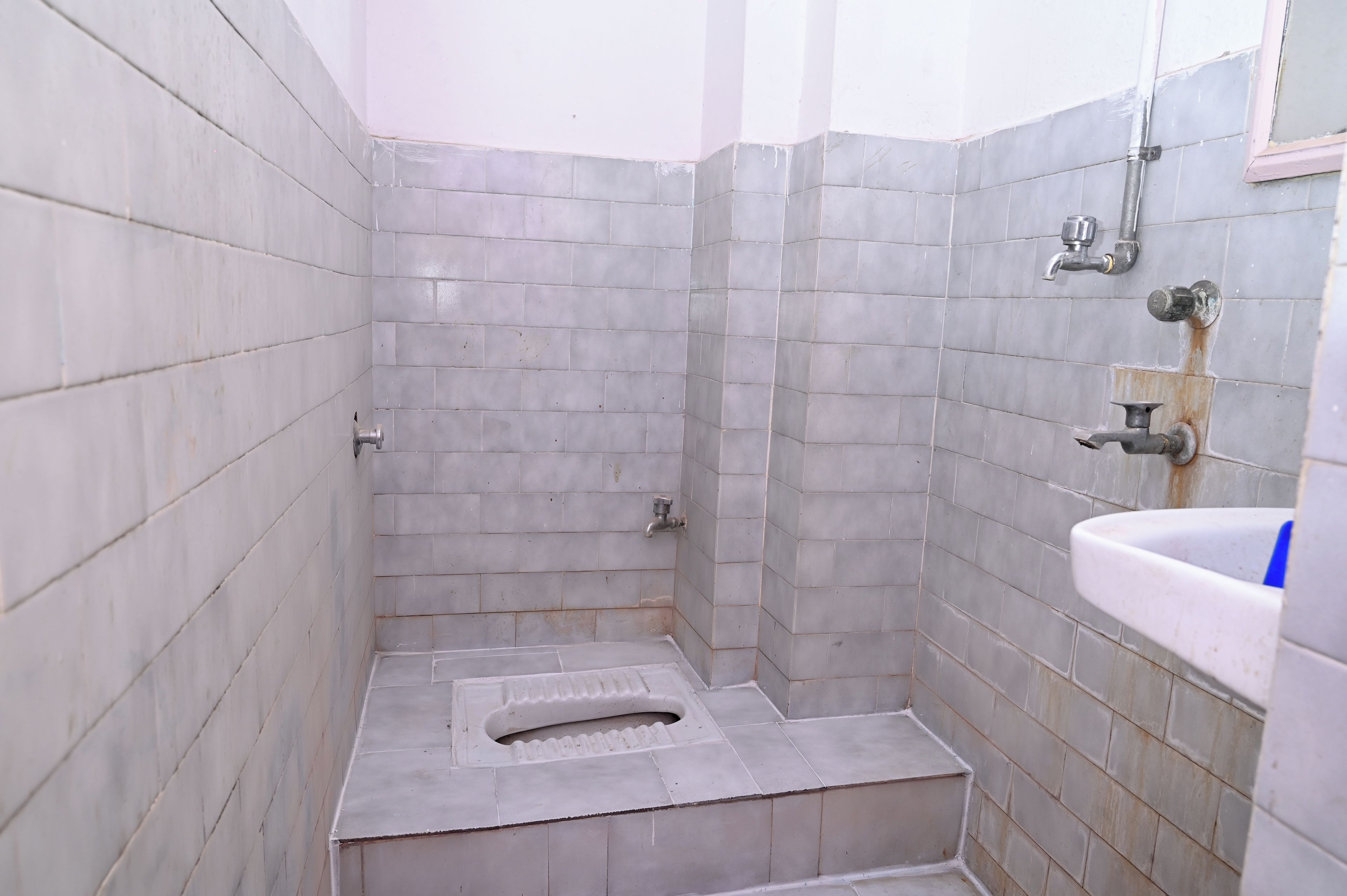 A bathroom with tiled walls, a shower area, and a sink.