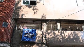 A building with a blue sign for Hotel Bluebell Inn, a brick tower, and a garage door with a motorcycle parked outside.