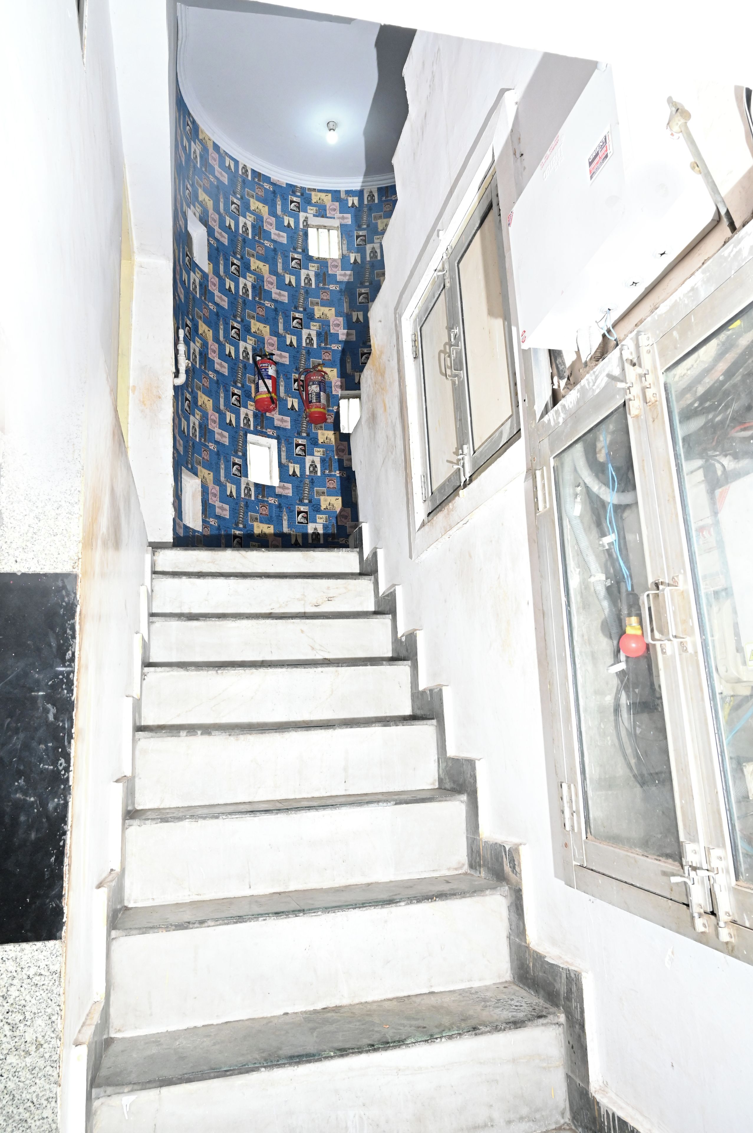Eine Treppe führt zu einem Raum mit einer gemusterten Wand und einer Tür mit einem Fenster.