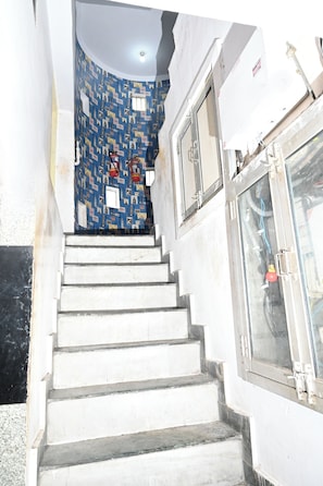 A staircase leading to a room with a patterned wall and a door with a window. - Hotel Bluebell one by M.B. Hotel Resorts (Lucknow)