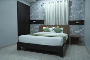 Un dormitorio con una cama, una mesita de noche, un estante en la pared y una puerta.
