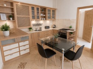 Une cuisine moderne avec des meubles en bois, une table à manger en verre et des chaises noires.