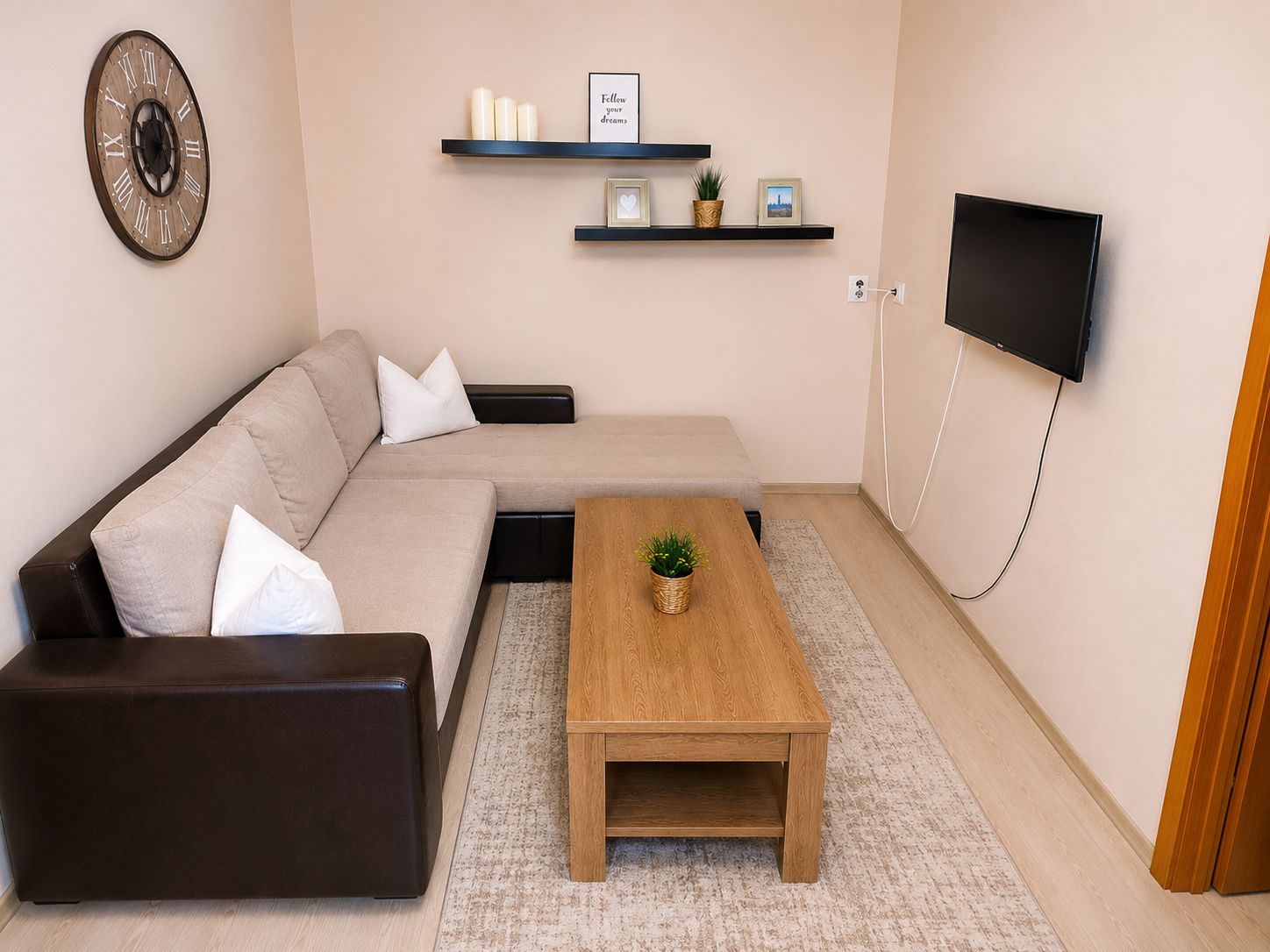 Un salon moderne comprenant un canapé, une table basse, un téléviseur et des étagères murales ornées d’objets décoratifs.