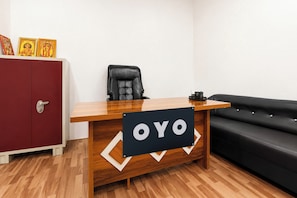 Una recepción con un cartel que dice 'OYO', en una habitación con un armario rojo, un sillón de cuero negro y un sofá negro.