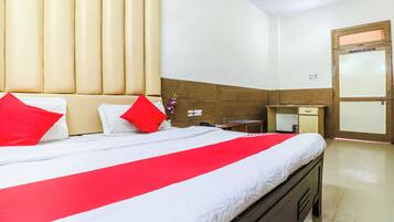 Habitación de hotel con cama, mesita de noche, escritorio, silla, armario y puerta.