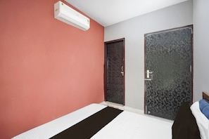 A bedroom with a bed, an air conditioner, and two doors. - Hotel O PARK'S HOTEL (Moradabad)