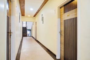 A hallway with a wooden door on the right, a number plate above it, and a staircase at the end. - Hotel O Rama Executive (Mahabaleshwar)