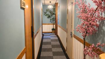 Un pasillo de hotel con alfombra a cuadros, puertas de madera y un árbol de cerezo.