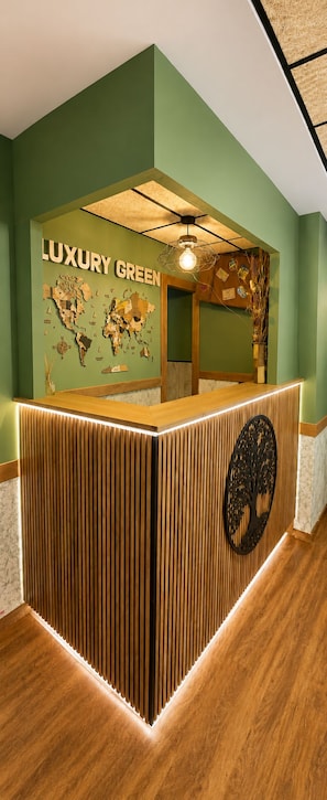 A reception desk with a world map and the text 'LUXURY GREEN' on the wall. - Hostal Luxury Green Madrid (MADRID)