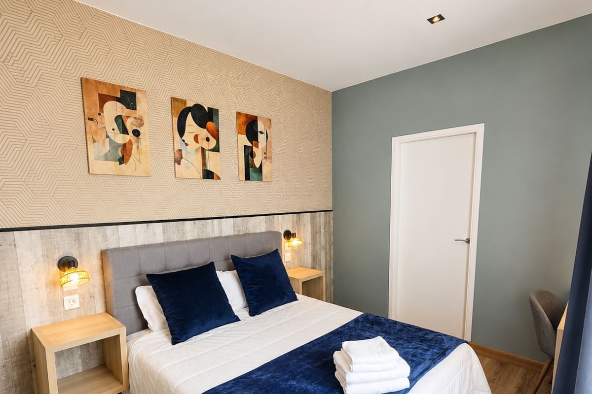 A modern bedroom with a bed, two bedside tables, a wall-mounted artwork, and a door.