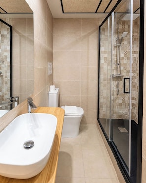 A modern bathroom with a large sink, toilet, and glass-enclosed shower. - Hostal Luxury Green Madrid (MADRID)