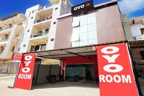 A hotel named OYO with a red awning and signage, a multi-story building with balconies, and a clear blue sky. - Hotel O New Star Hotel (Gurugram)
