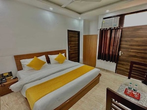 Habitación de hotel con cama, mesita de noche, armario y una pequeña mesa con botellas.