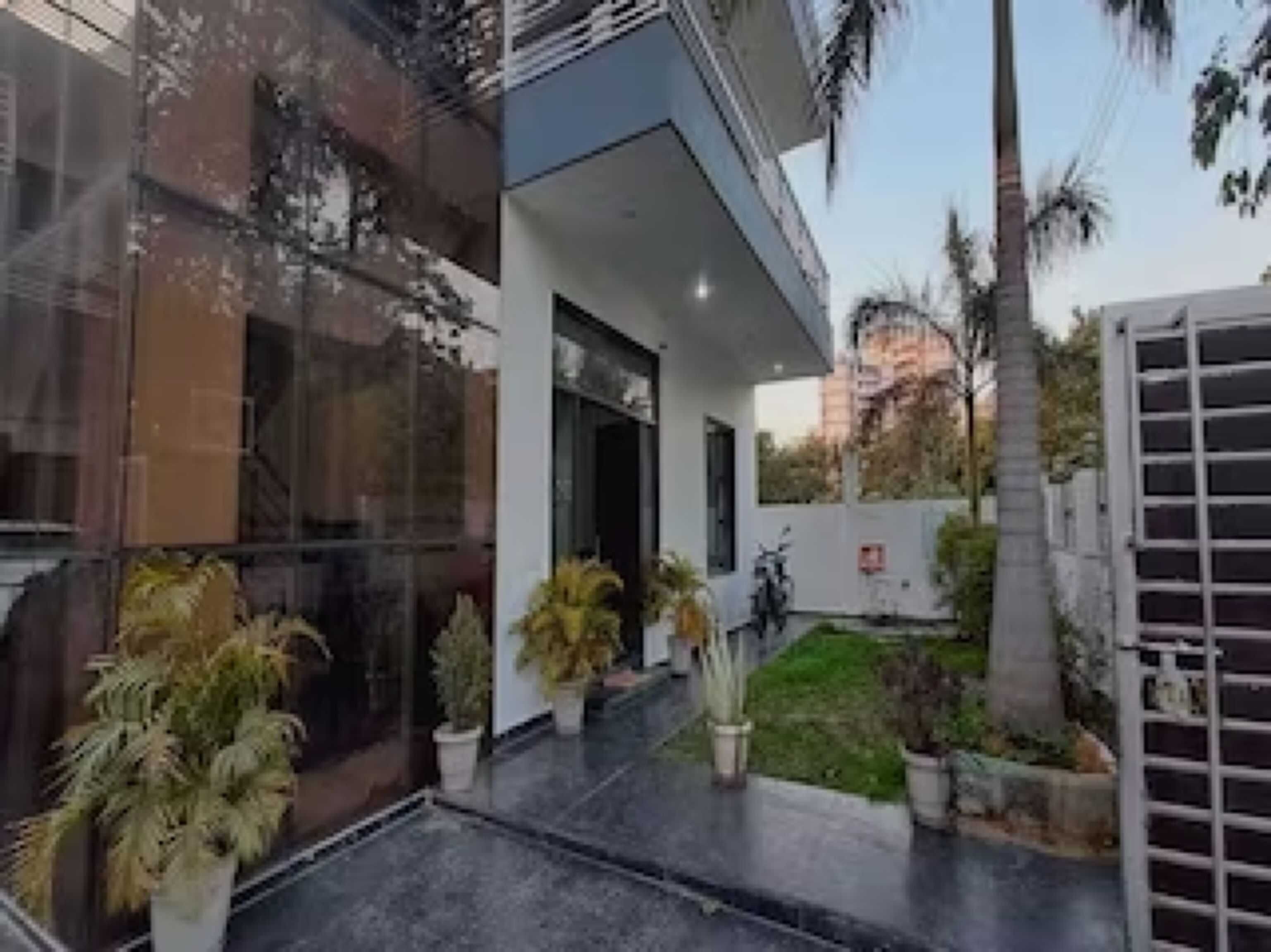 A modern building with large windows, a covered outdoor area, and potted plants.