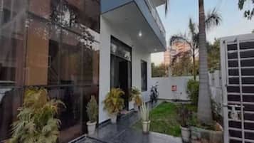 Un edificio moderno con grandes ventanales, un espacio exterior cubierto y plantas en macetas.