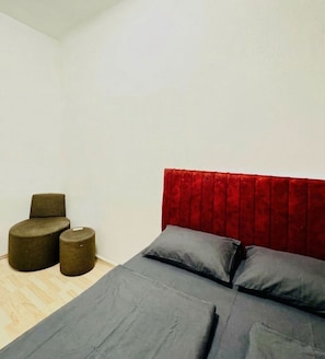 A bedroom with a bed, two ottomans, and a red headboard. - The Vienna Pause Private Room for Two (Wien)
