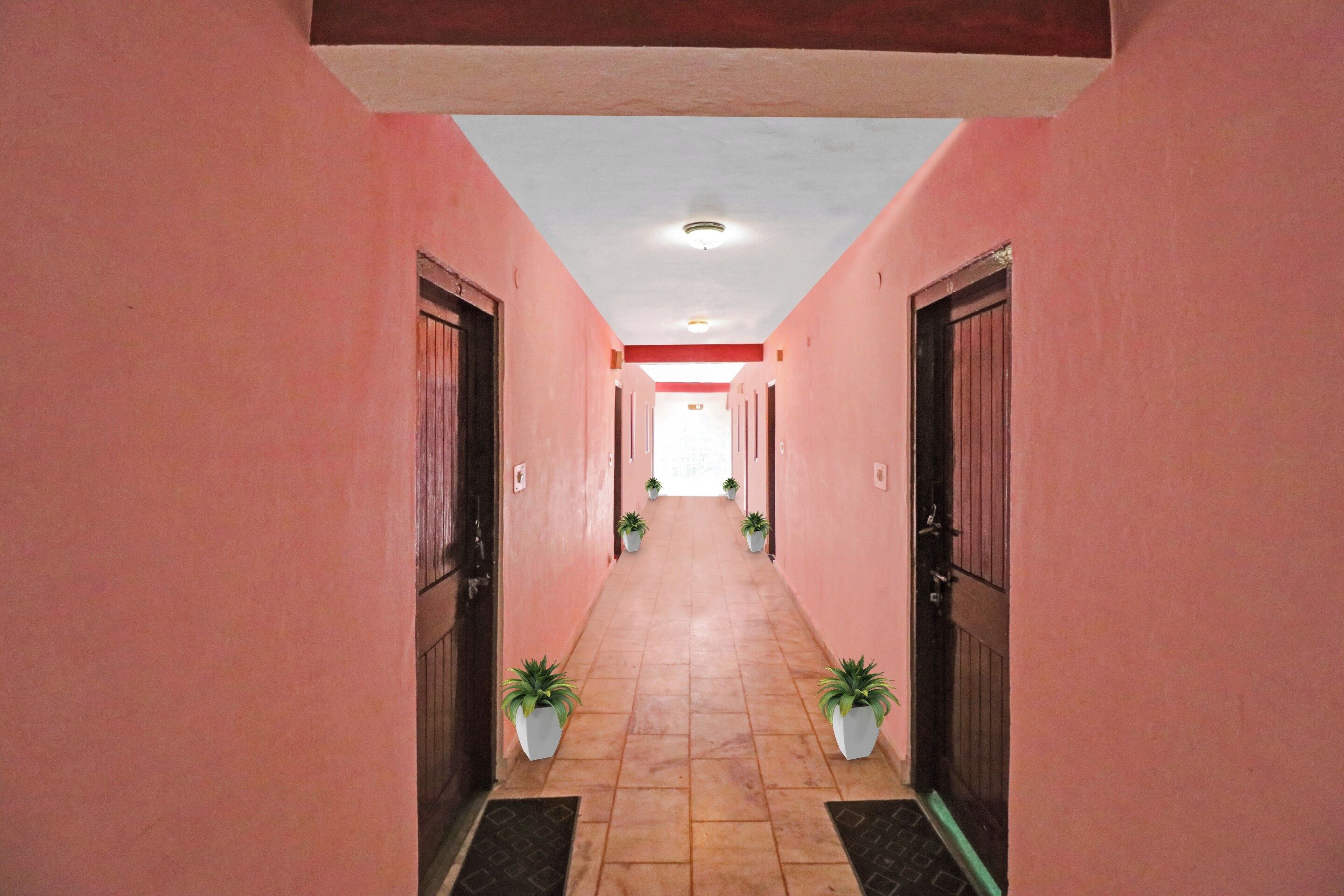 Un couloir aux murs roses, au sol carrelé et avec des portes de chaque côté.